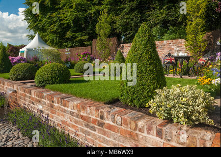 En cascade de l'eau du petit ruisseau, pelouse, fort boules & thé pour deux sous le soleil de son "un reflet de la vie" - show garden RHS Flower Show, Tatton Park, Angleterre, Royaume-Uni. Banque D'Images