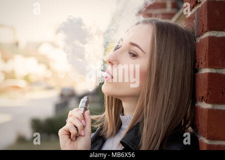 Jeune femme de fumer la cigarette électronique dans la ville Banque D'Images