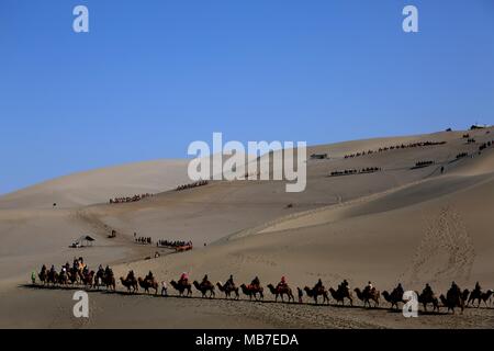 Nanjing, Chine, province de Gansu. 5ème apr 2018. Les touristes à cheval sur des chameaux visiter la montagne Mingsha et Crescent zone pittoresque de Printemps à Dunhuang, nord-ouest de la Chine, la province du Gansu, le 5 avril 2018. La Chine a vu plus de 100 millions de voyages touristiques au cours des trois jours de festival Qingming, en hausse de 8,3 pour cent par rapport à l'an dernier, maison de vacances, selon le ministère de la Culture et du tourisme. Credit : Zhang Xiaoliang/Xinhua/Alamy Live News Banque D'Images