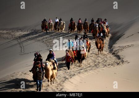 Nanjing, Chine, province de Gansu. 5ème apr 2018. Les touristes à cheval sur des chameaux visiter la montagne Mingsha et Crescent zone pittoresque de Printemps à Dunhuang, nord-ouest de la Chine, la province du Gansu, le 5 avril 2018. La Chine a vu plus de 100 millions de voyages touristiques au cours des trois jours de festival Qingming, en hausse de 8,3 pour cent par rapport à l'an dernier, maison de vacances, selon le ministère de la Culture et du tourisme. Credit : Zhang Xiaoliang/Xinhua/Alamy Live News Banque D'Images