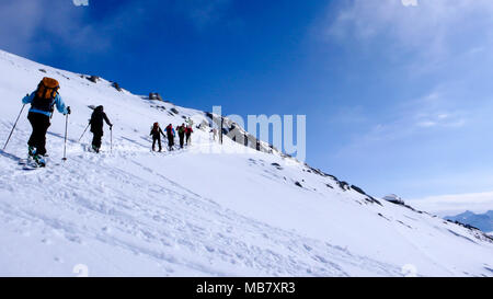 Groupe de randonneurs, hommes et femmes sur leur façon d'un haut sommet alpin sur une belle journée d'hiver Banque D'Images