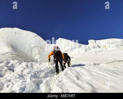 Les alpinistes sur un glacier raide sur leur façon d'un haut sommet alpin tôt le matin Banque D'Images