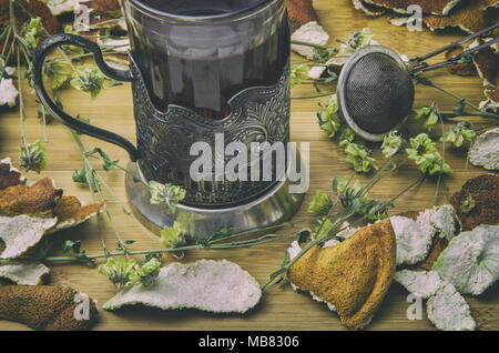 Gros plan du plateau vintage tasse à thé avec les zestes d'agrumes, sec et de fleurs sur table en bois. vintage des effets de filtre. Banque D'Images