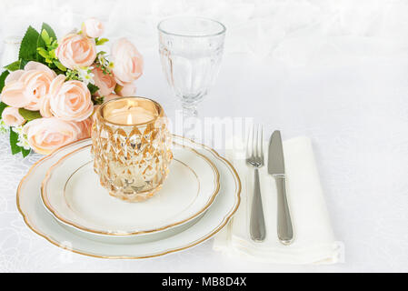 Table joliment décorée avec des assiettes en porcelaine blanche, verres, couverts, nappes et fleurs roses sur les nappes de luxe, avec l'espace de copie Banque D'Images