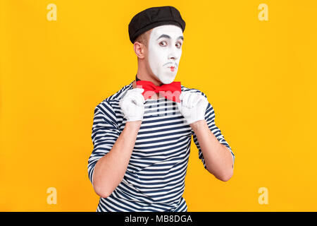 Bow Man mime de l'égalité et à la recherche à l'appareil photo. Émotions et sentiments concept. Tourné à l'intérieur, fond jaune Banque D'Images