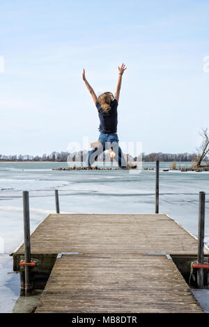 Jeune fille sautant par l'eau avec bonheur du printemps Banque D'Images