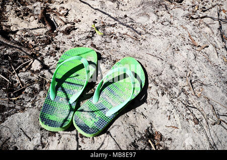 Se sentir abandonné. Green thongs flip flops on beach Banque D'Images