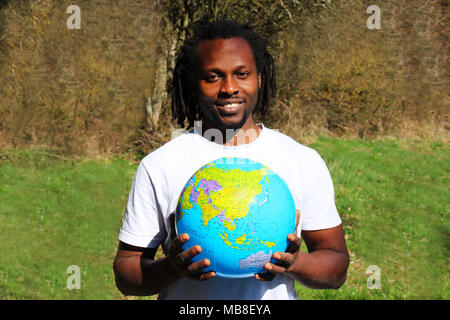 A smiling young man tient le monde globe dans ses mains Banque D'Images