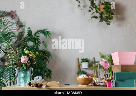 Image de la fleuriste avec vase de fleurs, guimauve sur fond de plantes d'intérieur Banque D'Images