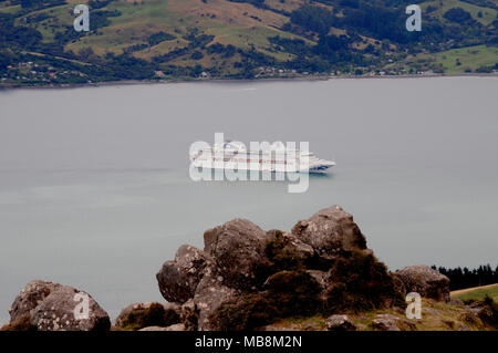 Vue vers le bas pour un navire de croisière ancré à l'approche prudente pour la petite ville d'Akaroa sur la péninsule de Banks près de Christchurch en Nouvelle-Zélande. Banque D'Images