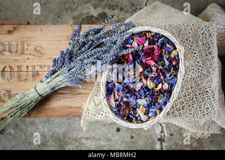 Bouquet de fleurs de lavande séchées et confetti dans un panier sur boîte en bois Banque D'Images