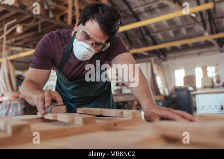 Jeune artisan bois ponçage habilement dans son grand atelier Banque D'Images