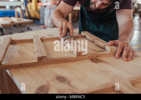 Artisan habilement le sablage d'un morceau de bois dans son atelier Banque D'Images