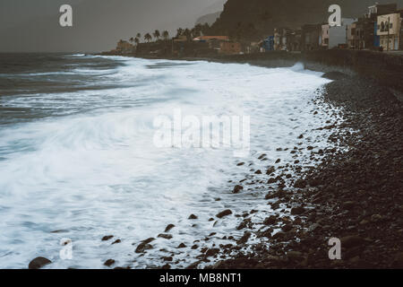 Les vagues de l'océan avec pulvérisation de soufflage roulant sur la côte volcanique rocheux. Ribeira Grande Village Banque D'Images