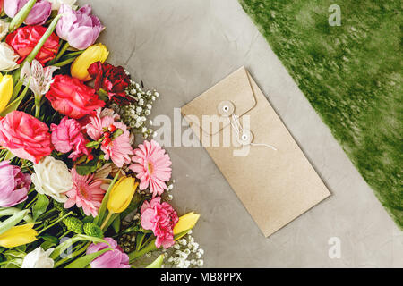 Enveloppe naturelle à côté de fleurs colorées sur une table de travail du fleuriste avant la Saint-Valentin Banque D'Images