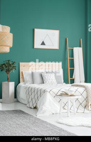 Lit en bois à côté de l'usine contre mur vert avec l'intérieur de l'affiche dans la chambre avec bain Banque D'Images