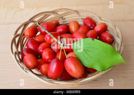Produits frais, fruits mûrs avec cornouiller à feuilles vert dans un panier en osier sur fond de bois, vue en gros Banque D'Images