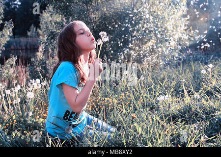 Teen girl blowing seeds à partir d'une fleur de pissenlit spring park Banque D'Images