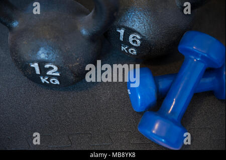 Deux kettlebells en fonte et fer enduit de néoprène deux haltères courtes, utilisé pour réveil musculaire, aérobic et de musculation, placé sur un tapis noir Banque D'Images