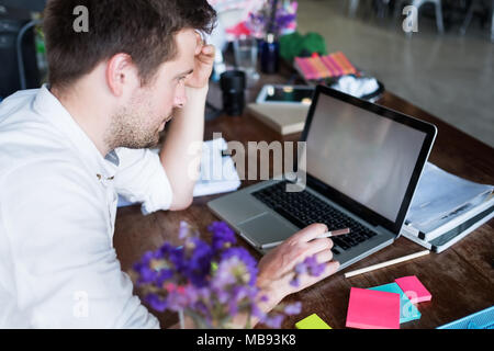 Caucasian man working on laptop assis à sa place de bureau moderne. Concept de jeunes utilisant lieu de coworking. Banque D'Images