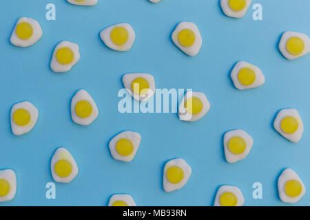 Bonbons bonbons oeufs au plat sur fond bleu lumineux au plafond Banque D'Images