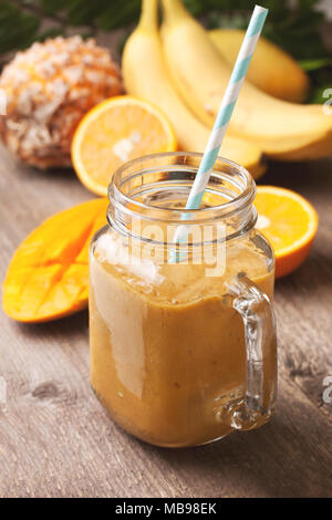 Avec smoothie fruits tropicaux : mangue, banane, ananas dans un pot Mason sur le vieux fond de bois Banque D'Images