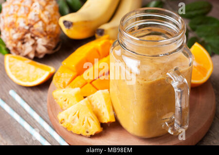Avec smoothie fruits tropicaux : mangue, banane, ananas dans un pot Mason sur le vieux fond de bois Banque D'Images