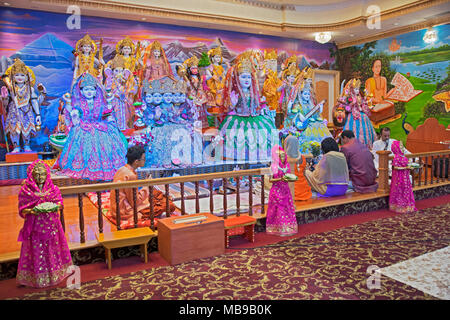 Trois fidèles et un prêtre, sur l'autel en priant et en méditant sur le Mandir Tulsi dans South Richmond Hill, Queens, New York.des statues, des dieux, godd Banque D'Images