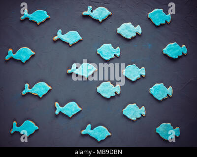 Ambiance festive, parfumé cookies dans la forme de dauphins et de poissons, couvertes de glace turquoise foncé sur une surface texturée Banque D'Images