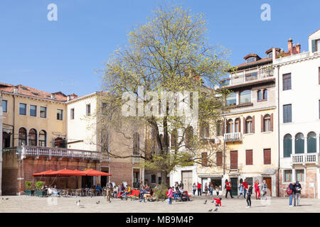 Campo San Polo, San Polo, Venise, Vénétie, Italie au printemps avec les habitants et leurs enfants le soleil brille, et reposant sur des bancs sous les arbres Banque D'Images