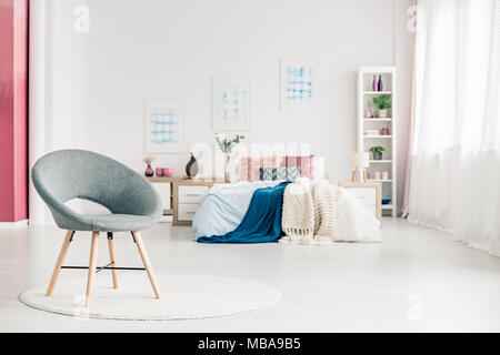 Chambre confortable avec intérieur Président Comité permanent gris sur blanc, rond, tapis, lit, posters, rose et blanc, murs rideaux et bibliothèque. Banque D'Images