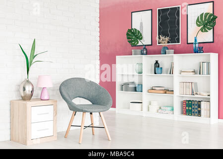 Chaise gris moderne appartement en open space avec intérieur blanc, Grande bibliothèque, mur de briques blanches et d'affiches Banque D'Images