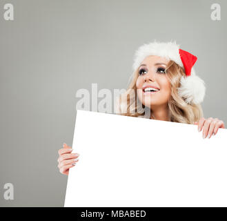 Belle femme de Noël avec du papier blanc avec fond copie vide de l'espace. Modèle heureux in Santa Hat, Noël Hiver Femme Banque D'Images