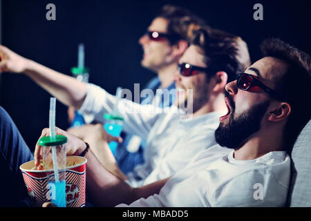 Groupe d'amis heureux assis dans le cinéma voir le film et eating popcorn Banque D'Images