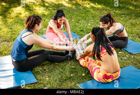 Quatre belles femmes motivés amis doing stretching exercice dans le parc de la ville. Banque D'Images