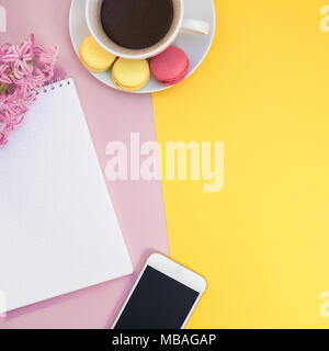 Télévision créative fixer photo de tasse de café avec des macarons et un bloc-notes avec copie espace sur fond jaune et rose style minimal Banque D'Images