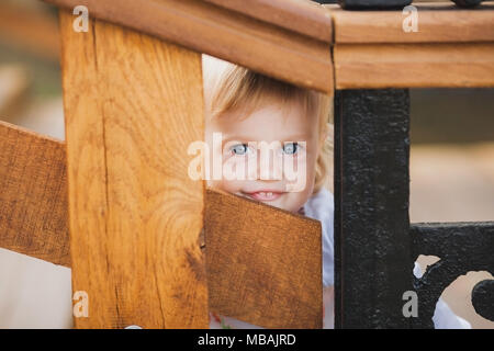 1 ans peu mature man palaing le jeu mobile extérieur dès les beaux jours chauds d'été. Closeup portrait of délicat visage de blond bébé cacher f Banque D'Images