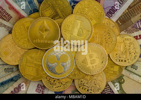 Pile de pièces d'or assorties cryptocurrency sur fond de papier dans le monde ancien billets vus du dessus dans un concept de finances numérique Banque D'Images