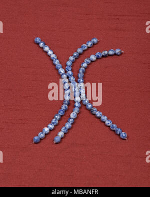 Facettes perles ronde sodalite et string rouge sur fond de tissu Banque D'Images