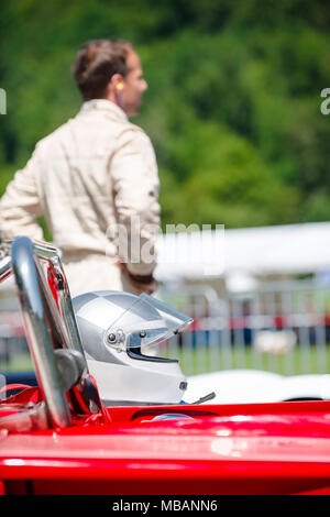 Homme non identifiables en fonction de la course de voiture de course derrière son casque et, en attendant le départ. Selective focus sur le casque à l'avant-plan. Banque D'Images