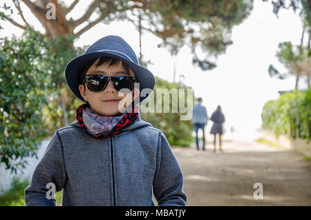 Un portrait d'un jeune garçon portant un bandana, des lunettes de soleil et chapeau d'été. Banque D'Images