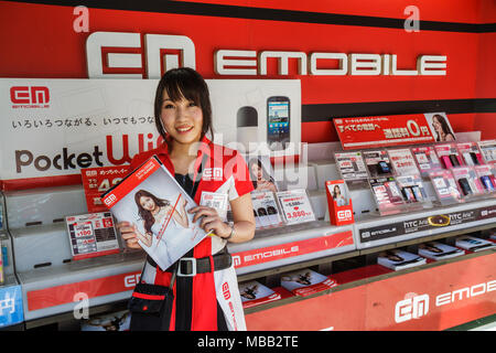 Tokyo Japon,Orient,Shinjuku,E Mobile,Emobile,mobile magasin de téléphonie mobile,vendeurs,stalles stands marché achat vente,vente d'affichage,femme asiatique Banque D'Images