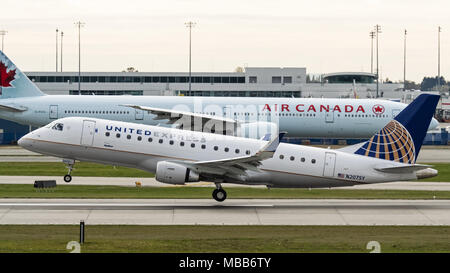 Richmond, Colombie-Britannique, Canada. 29Th sep 2017. Un United Express Embraer E175 (N207SY) narrow-corps-couloir unique avion de ligne bimoteur, exploité par SkyWest Airlines, décolle de l'Aéroport International de Vancouver. Dans l'arrière-plan un Air Canada Boeing 777-300ER (C-FIVX) circule le long de la piste. Credit : Bayne Stanley/ZUMA/Alamy Fil Live News Banque D'Images