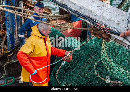 Schull, Irlande. 19 avril, 2018. Sur un froid, mais sec et venteux nuageux jour, deux pêcheurs préparent leurs filets avant de partir à la pêche. Il y aura des averses ce soir cette nuit avec les bas de 6°. Credit : Andy Gibson/Alamy Live News. Banque D'Images