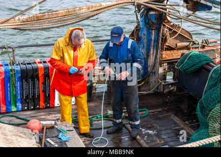 Schull, Irlande. 19 avril, 2018. Sur un froid, mais sec et venteux nuageux jour, deux pêcheurs préparent leurs filets avant de partir à la pêche. Il y aura des averses ce soir cette nuit avec les bas de 6°. Credit : Andy Gibson/Alamy Live News. Banque D'Images