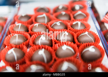 Lisse et brillant gourmet chocolat blanc lait brandy les truffes sur un plateau dans une boulangerie chocolatier candy shop magasin. Banque D'Images