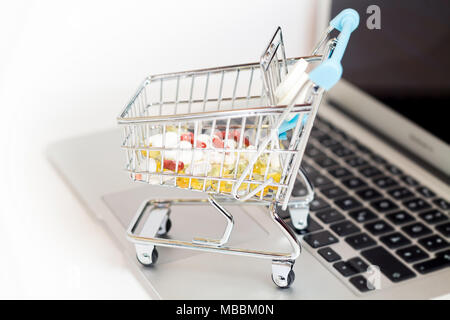 Les suppléments en ligne shopping concept pharmaceutique, shopping-cart mis sur ordinateur portable isolé Banque D'Images