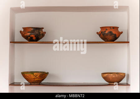 Quatre pots d'argile placé sur deux étagères en bois. derrière un mur blanc Banque D'Images