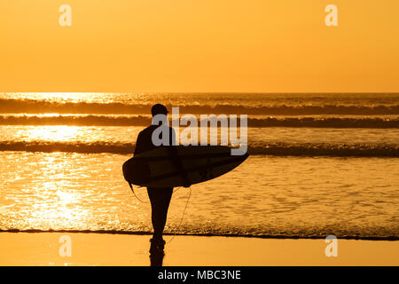 Aller Surfer coucher de soleil sur la plage de Fistral, Newquay, Cornwall, Angleterre, Grande-Bretagne, Royaume-Uni. Banque D'Images