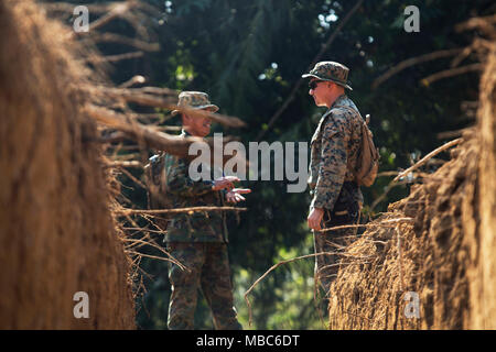 Le Caporal des Marines des États-Unis. Michael Troll, originaire de Charlotte (Caroline du Nord), traite de la conception d'une tranchée avec un ingénieur de combat du Royaume de Thaïlande au camp de Ban Chan Khrem, Thaïlande, le 14 février 2018. Les Marines américains travaillent aux côtés des ingénieurs thaïlandais à construction de traverses de cours d'eau pour permettre aux véhicules et le personnel d'urgence de voyager efficacement pendant la saison des pluies en Thaïlande. Troll est l'ingénieur de combat pour lutter contre le 4 Bataillon logistique, 3e Groupe logistique maritime, au cours de l'échange d'experts en la matière entre les ingénieurs de combat des États-Unis et le Royaume de Thaïlande au cours de l'effort s/n Banque D'Images